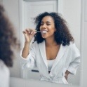 Woman looking in mirror for common symptoms of lip and tongue tie