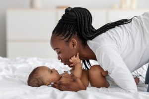 mother and baby playing on bed 